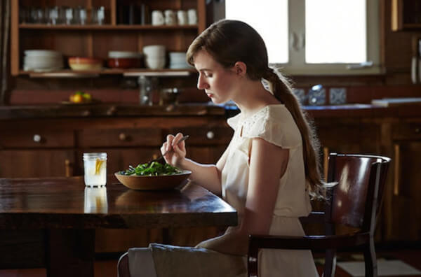 Дівчина їсть салат за столом