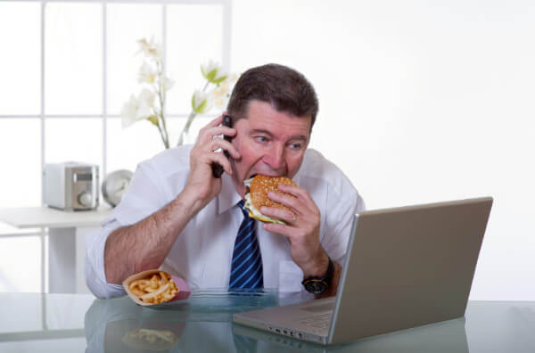 Чоловік їсть за комп'ютером