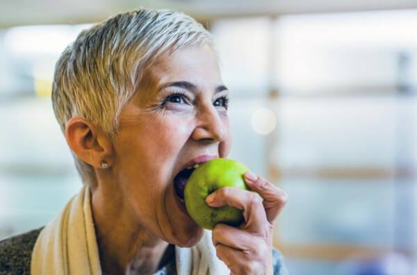 Жінка їсть яблуко