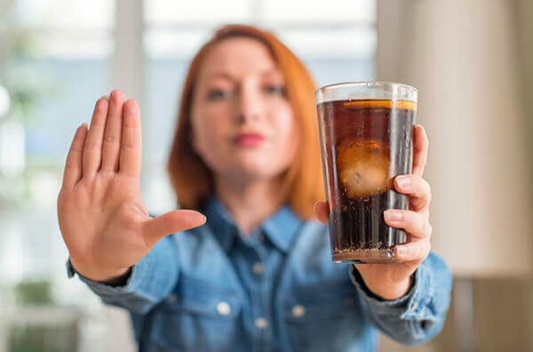 Жінка тримає склянку дієтичної кока-коли
