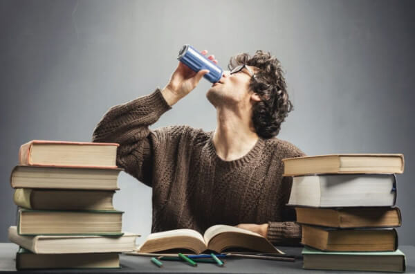 Чоловік за книжками п'є енергетичний напій