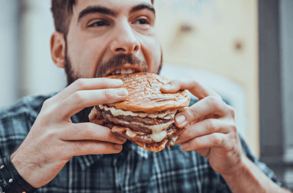 Чоловік їсть бургер