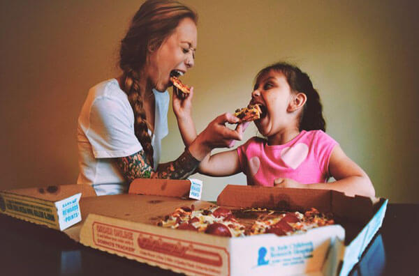 Мама і дочка їдять піцу