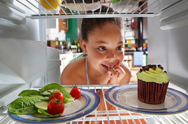 Дівчинка вибирає їжу з холодильника