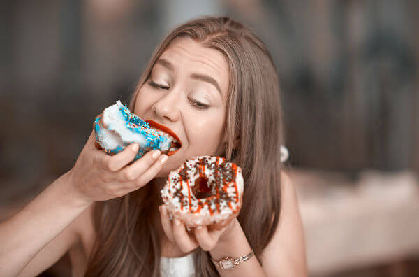 Жінка їсть пончики