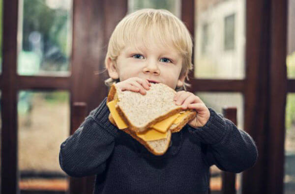 Хлопчик їсть сендвіч з сиром