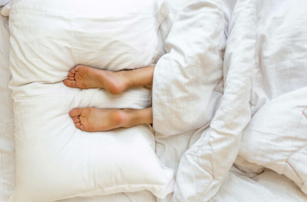 Людина спить ногами на подушці