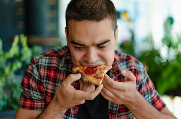 Чоловік їсть піцу