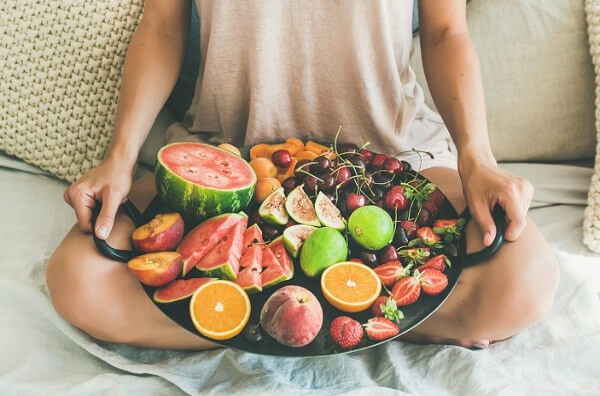 Жінка тримає тацю з фруктами