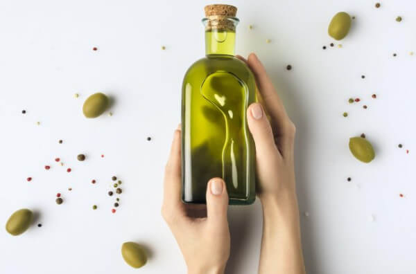 Пляшка оливкової олії у руках