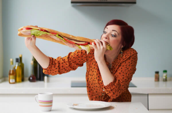 Жінка їсть величезний сендвіч