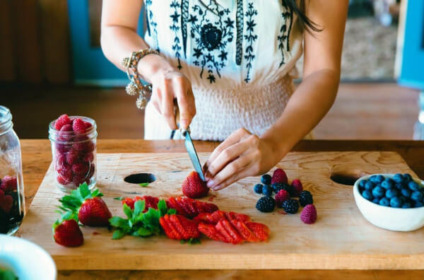 Жінка нарізає ягоди