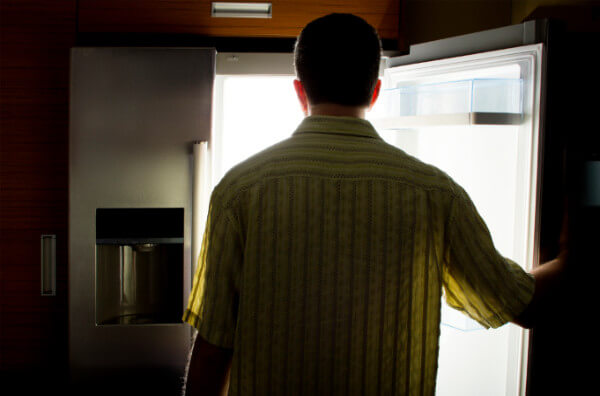 Чоловік стоїть перед холодильником