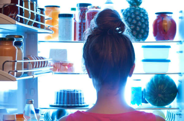 Жінка стоїть перед холодильником