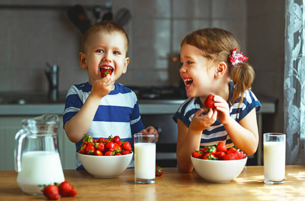 Діти їдять полуницю і молоко