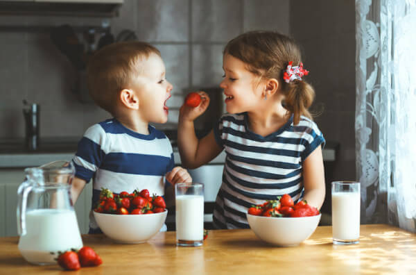 Діти їдять полуницю і п'ють молоко