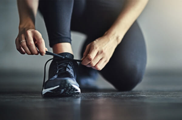 Жінка зав'язує шнурівку на спортивному взутті