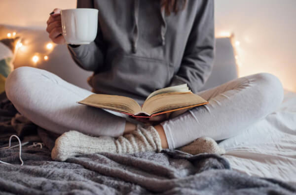 Жінка п'є чай і читає книжку