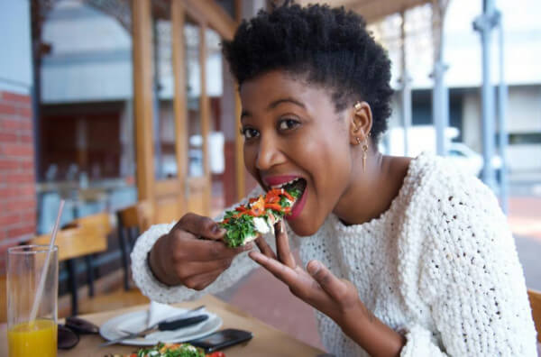 Жінка їсть тост з овочами