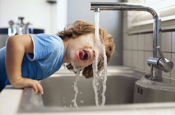 Дитина п'є воду з-під крану