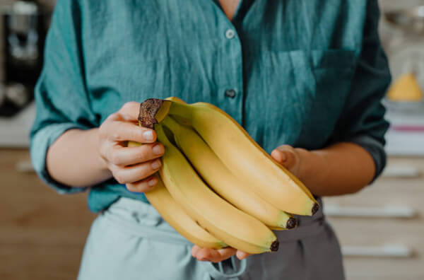 Жінка тримає у руках банани