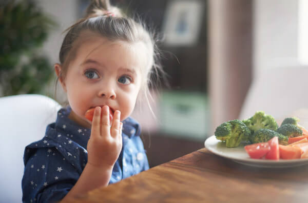 Дівчинка їсть помідор
