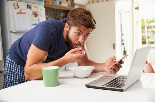 Чоловік їсть одночасно працюючи на комп'ютері