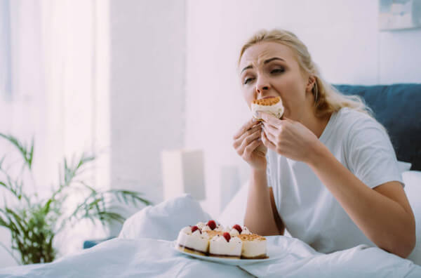 Жінка їсть торт у ліжку