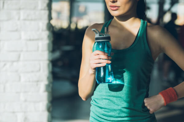 Жінка п'є воду під час тренування