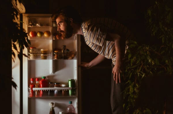 Чоловік заглядає у холодильник вночі