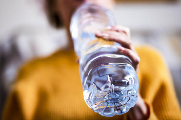 Жінка п'є воду з пляшку