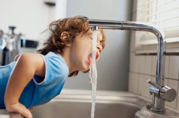 Дитина п'є воду з-під крану