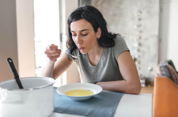 Жінка їсть суп