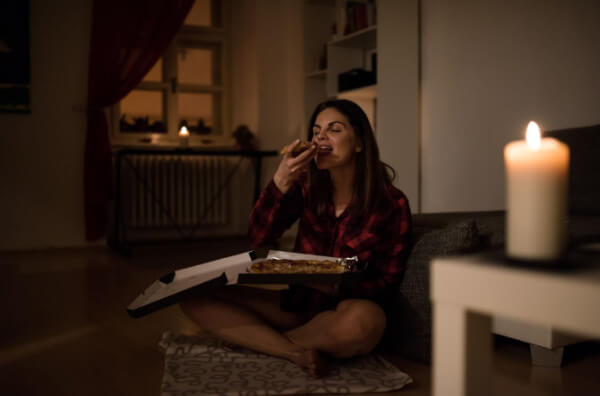 Жінка їсть піцу пізно ввечері