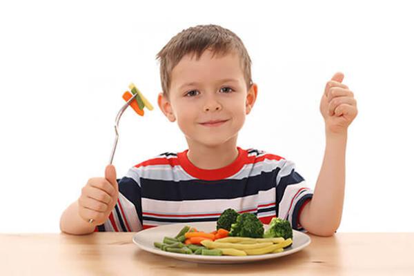 Хлопчик їсть овочі