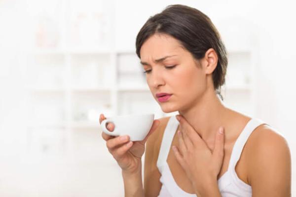 Жінка з хворим горлом п'є чай