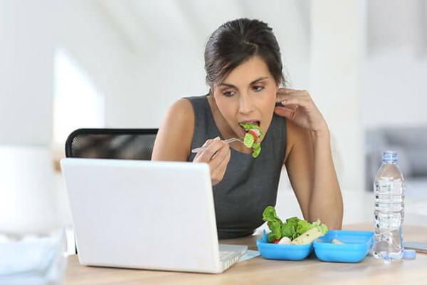 Жінка їсть салат перед екраном