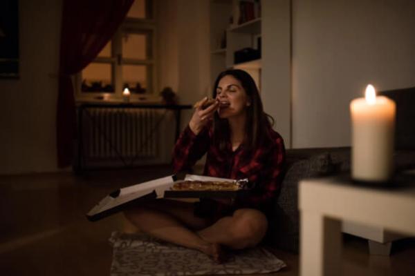 Жінка їсть піцу вночі