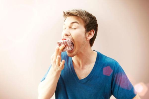 Чоловік їсть тістечко
